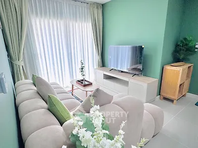 Modern living room with plush sofa, TV, and green accent wall