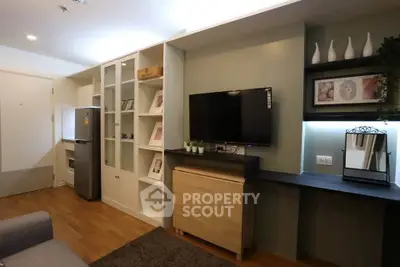 Modern living room with stylish decor and built-in shelving, featuring a flat-screen TV and cozy ambiance.