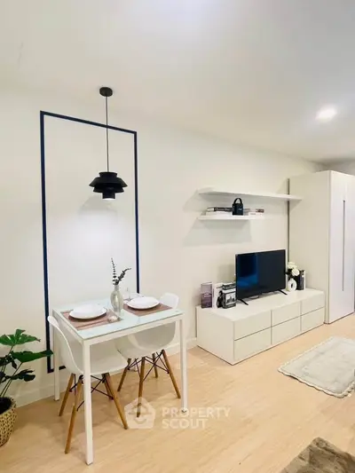 Modern living room with sleek furniture and dining area, featuring minimalist decor and a cozy ambiance.