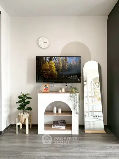 Modern living room with stylish decor, wall-mounted TV, and elegant mirror.