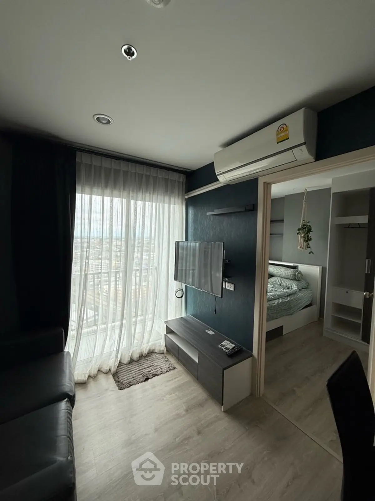 Modern living room with city view, sleek furniture, and cozy bedroom access