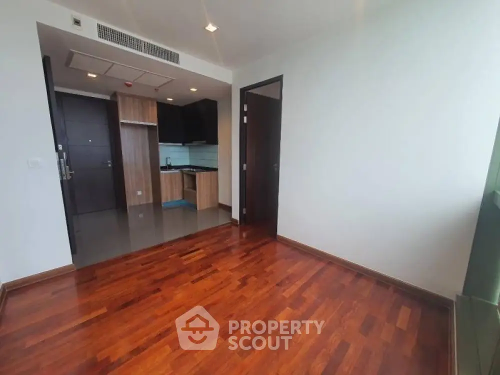 Spacious living room with polished hardwood floors leading to an open layout kitchen, perfect for modern living and entertaining.