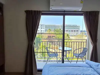 Cozy bedroom with balcony view overlooking Bangkok Hospital, featuring air conditioning and outdoor seating.