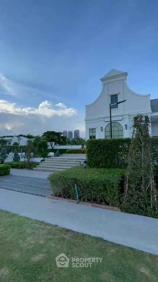 Elegant exterior of a luxury home with lush garden and clear blue sky.
