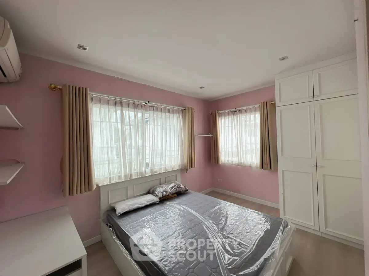 Cozy bedroom with pink walls, large windows, and ample storage in a modern home.