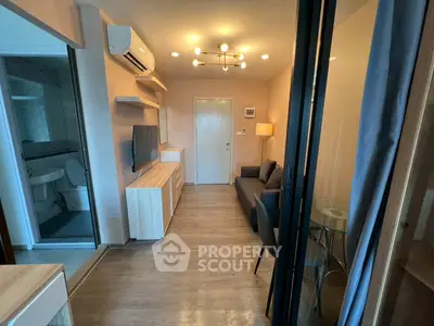 Modern living room with sleek furniture and air conditioning, adjacent to a compact bathroom.