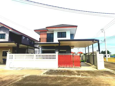 Modern two-story house with red gate and white fence in suburban neighborhood.