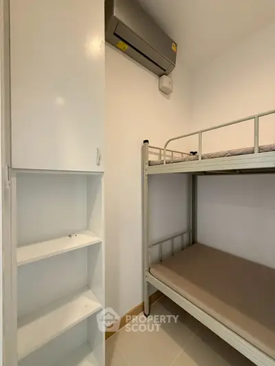 Compact bedroom with bunk bed and air conditioning unit, ideal for maximizing space in small apartments.