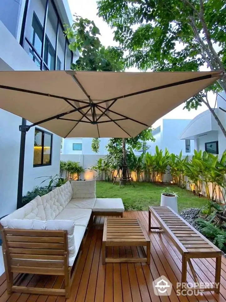 Charming garden patio with modern seating and large umbrella, perfect for outdoor relaxation.