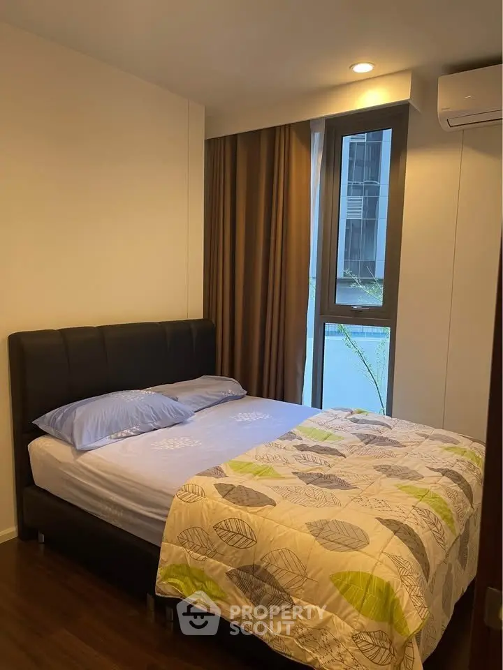 Cozy bedroom with modern decor and large window in a stylish apartment.