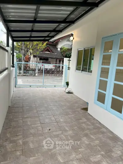 Charming covered patio with tiled flooring and blue-framed windows, perfect for outdoor relaxation.