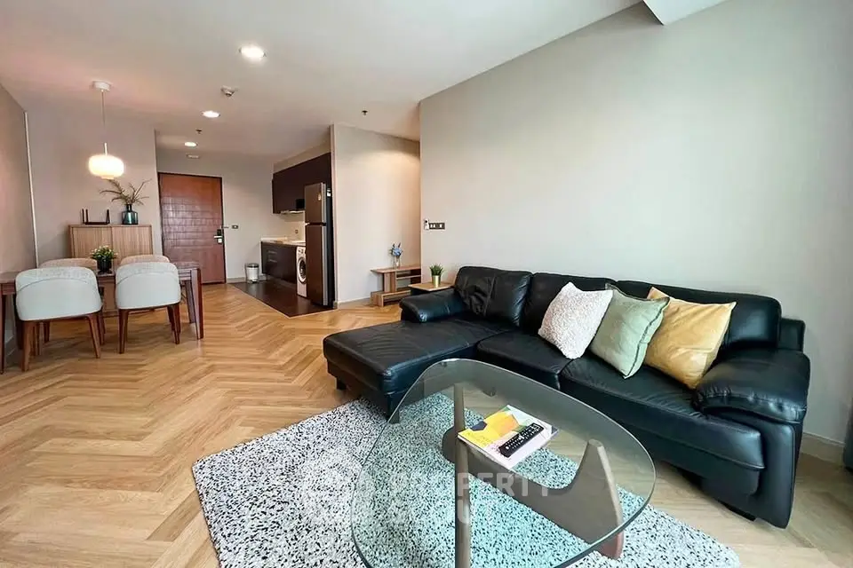 Modern living room with stylish black leather sofa and open kitchen layout in a contemporary apartment.