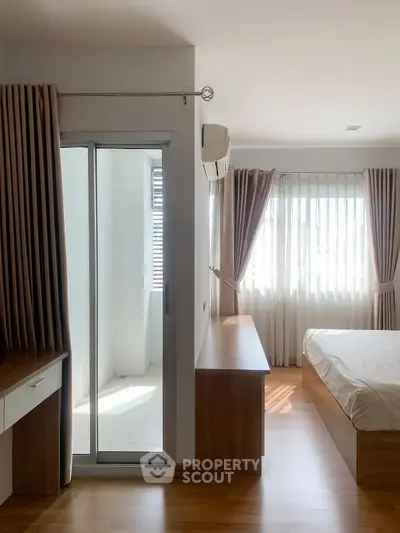 Bright and airy bedroom with wooden flooring and large windows for natural light.