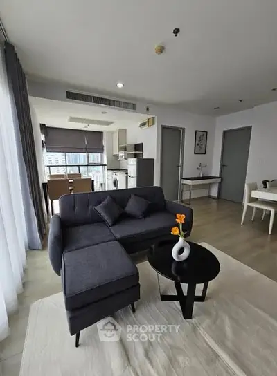 Modern living room with stylish furniture and open kitchen layout in a high-rise apartment.