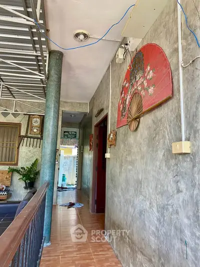 Charming rustic hallway with decorative fan and exposed concrete walls.
