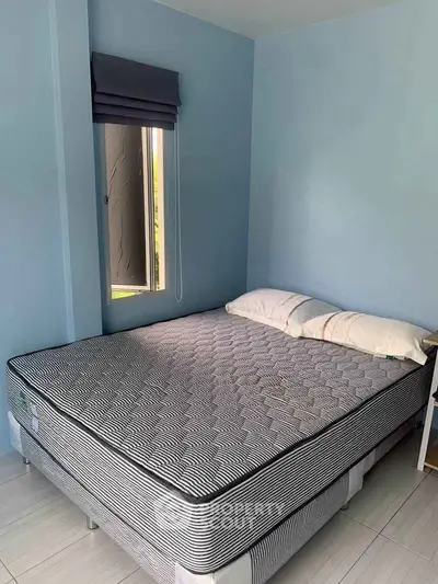 Cozy bedroom with a comfortable mattress and soft pillows in a serene blue setting.