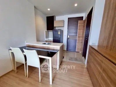 Modern kitchen with sleek design and dining area in compact apartment.
