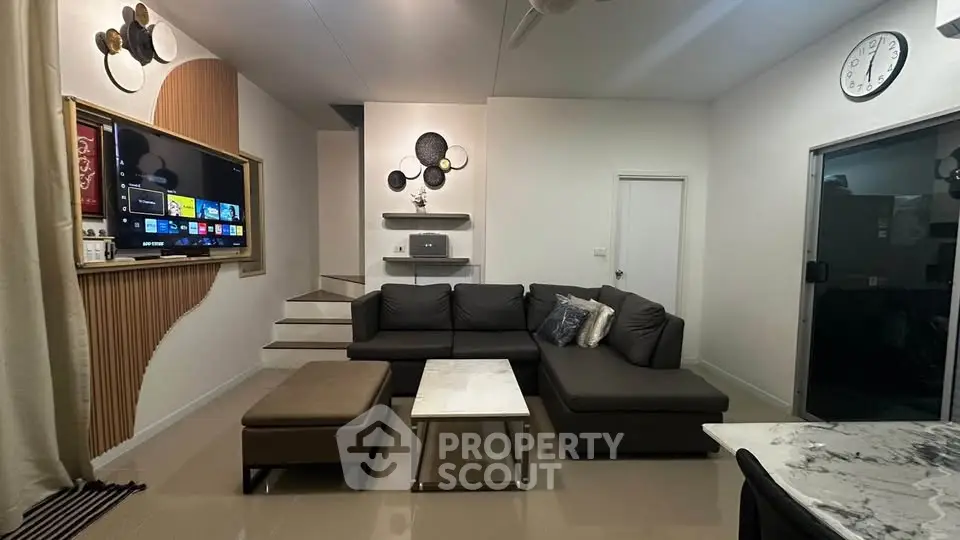 Modern living room with sleek sectional sofa and wall-mounted TV, featuring stylish decor and neutral tones.