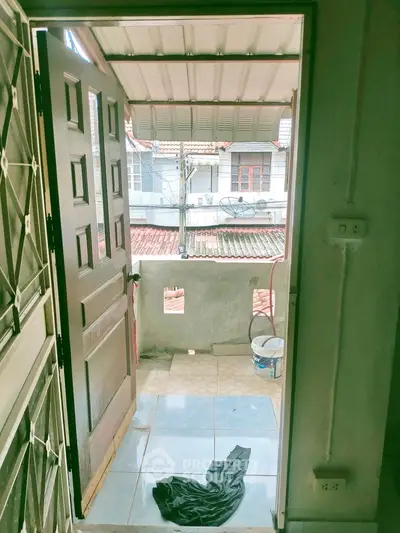 Charming balcony view with open door, showcasing cozy outdoor space and neighborhood rooftops.