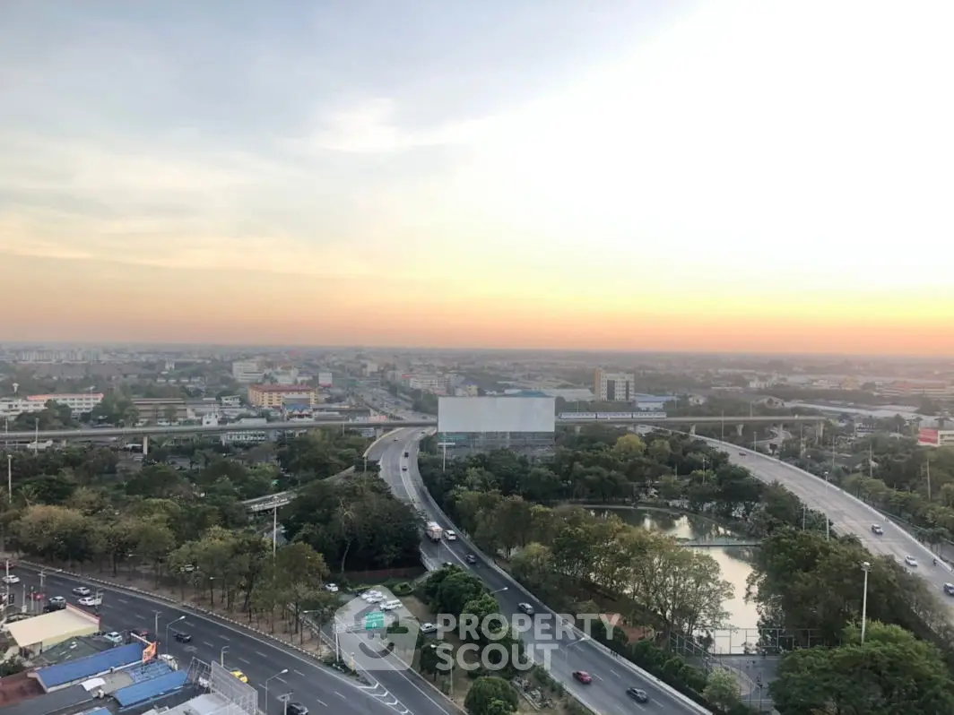 Stunning panoramic cityscape view with lush greenery and vibrant sunset.