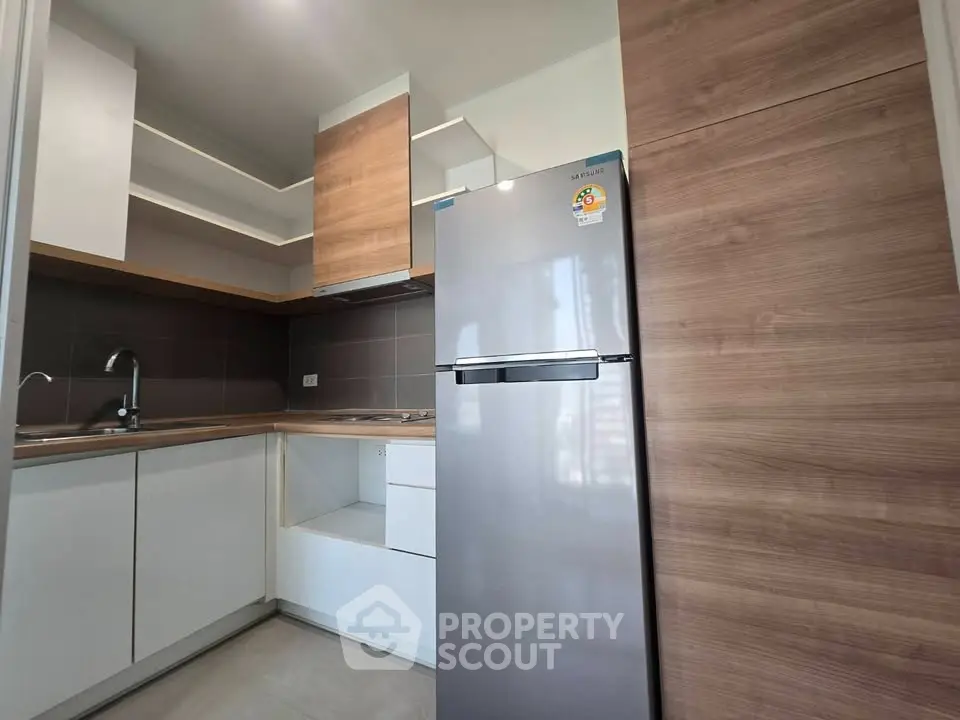 Modern kitchen with sleek cabinets and stainless steel fridge in a stylish apartment.
