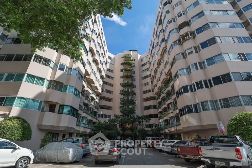 Stunning apartment building with ample parking and lush greenery, perfect for urban living.