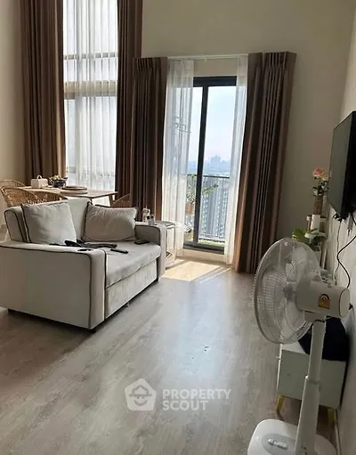 Bright living room with high ceilings and city view from balcony.