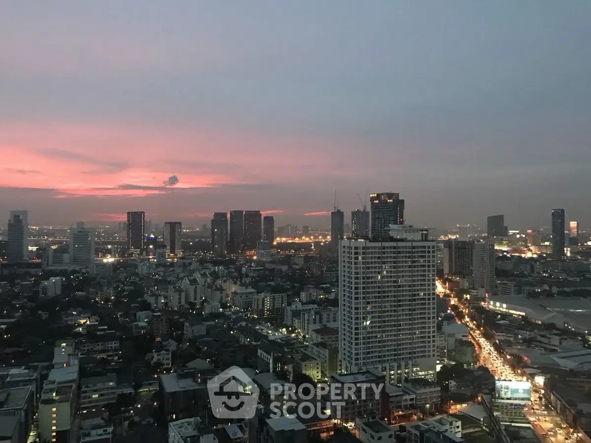 Stunning cityscape view at dusk with illuminated skyline and vibrant sunset hues.