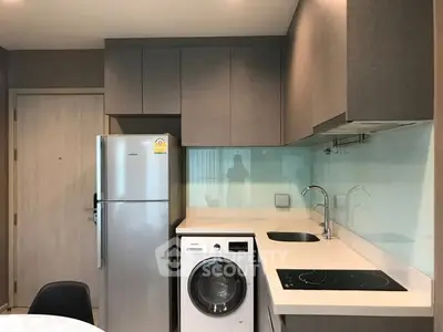 Modern kitchen with sleek cabinets, stainless steel fridge, and built-in washing machine.