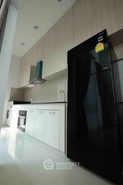 Modern kitchen with sleek black fridge and built-in oven in stylish apartment.