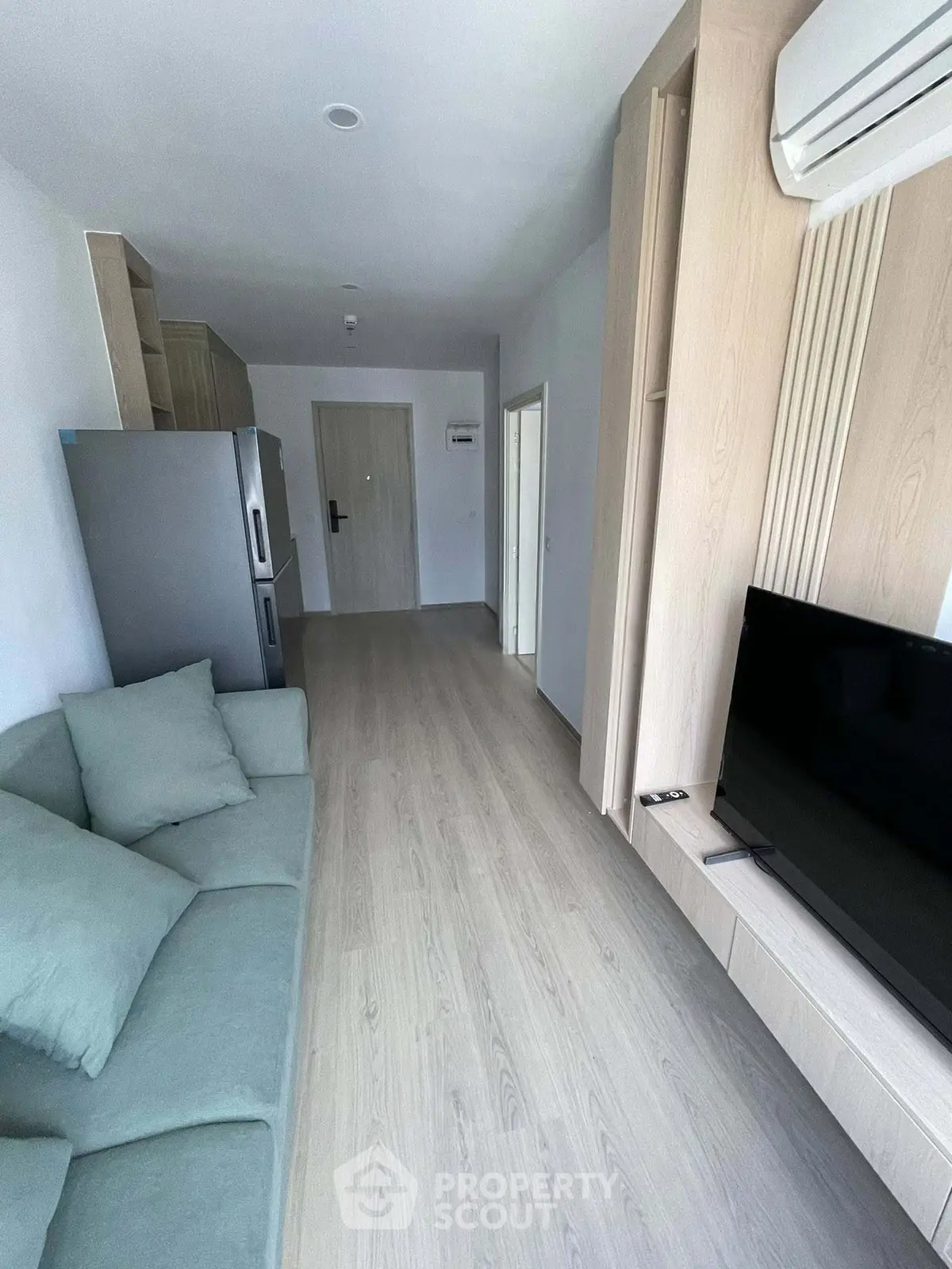 Modern living room with sleek design, featuring a cozy sofa, flat-screen TV, and air conditioning unit.