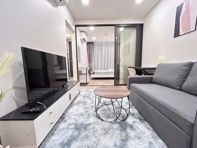 Modern living room with sleek furniture and open view to bedroom