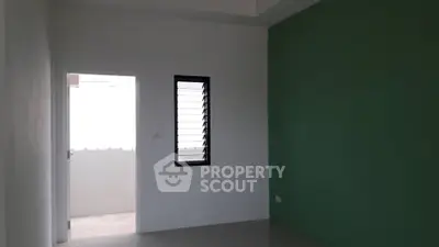 Minimalist empty room with green accent wall and louvered window