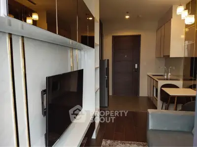 Modern living room with sleek TV setup and stylish kitchen area in open layout apartment.