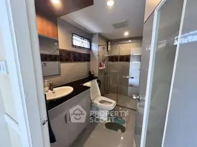 Modern bathroom with glass shower and sleek vanity in contemporary home.