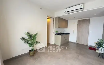 Modern living room with sleek tile flooring and compact kitchen area, featuring air conditioning and stylish decor.