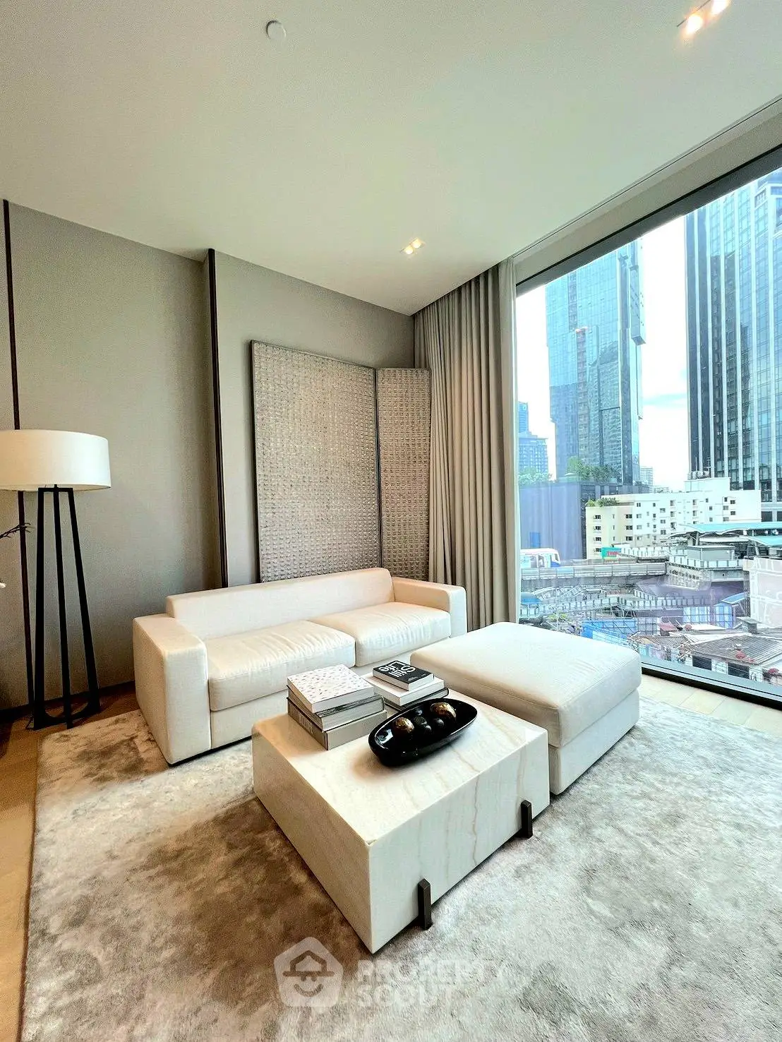 Luxurious modern living room with city view, featuring elegant white furniture and floor-to-ceiling windows.