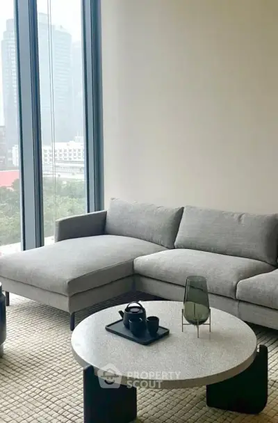 Modern living room with sleek gray sofa and city view, perfect for urban living.