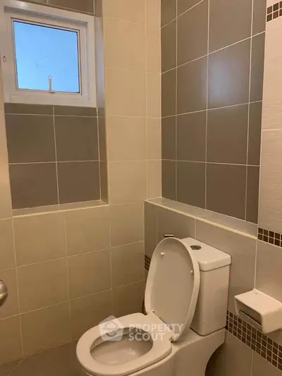 Modern bathroom with sleek tiles and a compact toilet design.