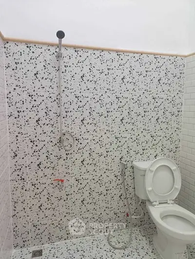 Modern bathroom with terrazzo tiles and showerhead, featuring a sleek toilet design.