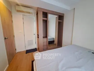 Cozy bedroom with wooden flooring and built-in wardrobe, perfect for modern living.