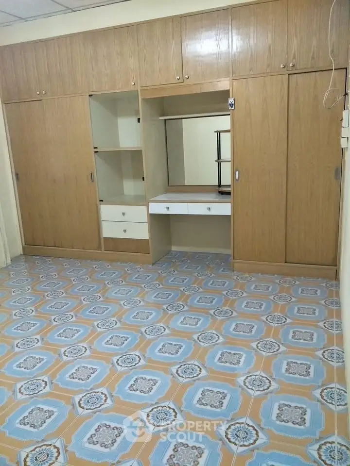 Spacious room with built-in wooden wardrobe and decorative tiled flooring
