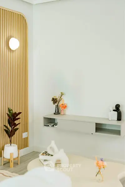 Modern living room with stylish decor and wall-mounted shelf, featuring elegant lighting and indoor plants.