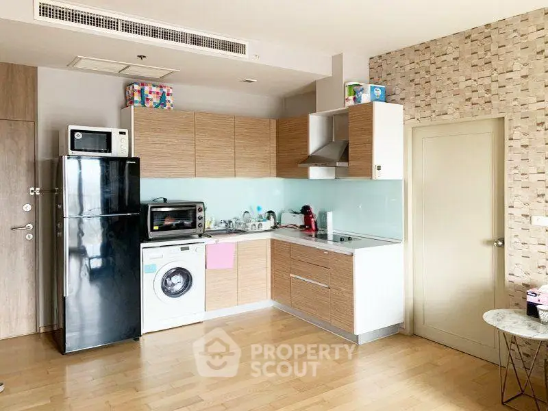 Modern kitchen with wooden cabinets, washing machine, and sleek appliances in a stylish apartment.