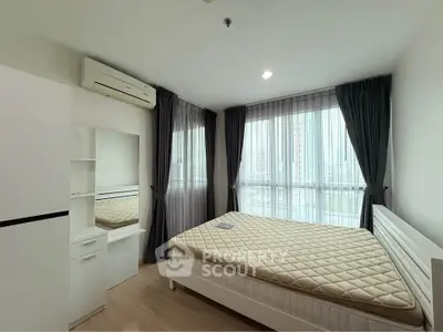 Spacious bedroom with large windows and modern furnishings in a bright apartment.