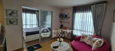 Charming living room with cozy seating and adjacent bedroom in modern apartment.