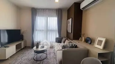 Modern living room with stylish decor and natural light, featuring a cozy sofa and sleek TV setup.