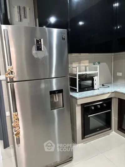 Modern kitchen with stainless steel fridge, oven, and microwave in sleek design.