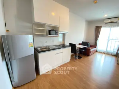 Modern apartment with sleek kitchen and cozy living area featuring a large window.