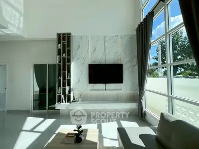 Modern living room with high ceilings, large windows, and stylish decor